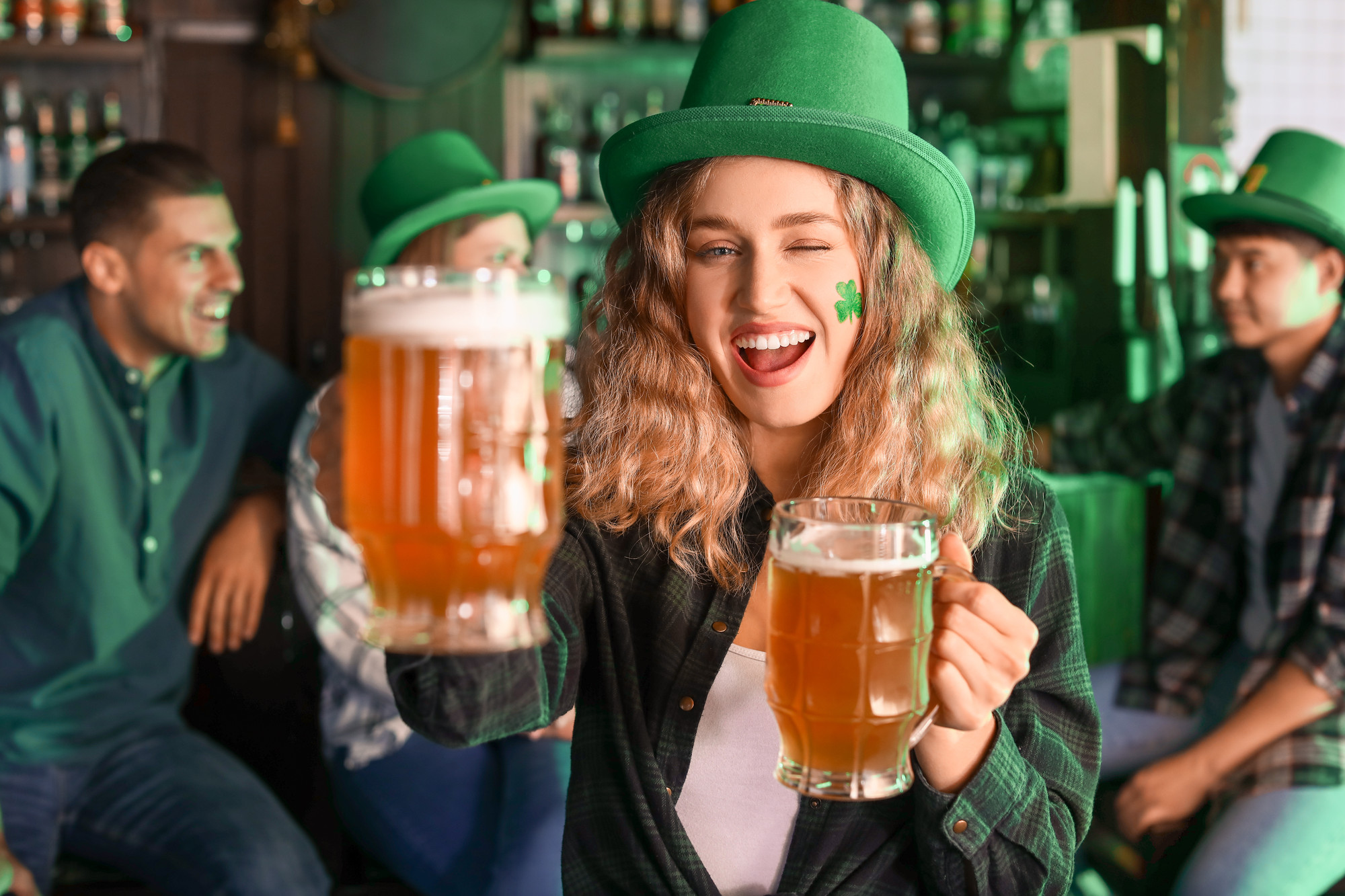 Young woman with beer celebrating St. Patrick’s Day in pub