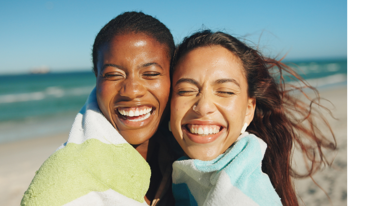 faces of two women smiling on beach