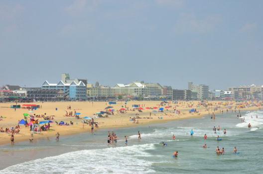 Ocean City MD beach with lifeguard stand and families playing in the surf